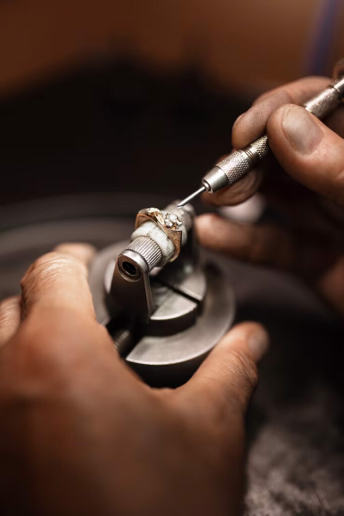 Jewellery crafting process with artisan engraving a gold ring by hand